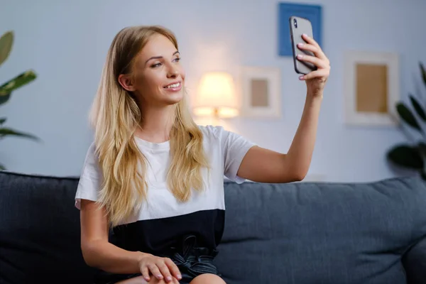 Használ a smartphone a nappaliban, a gyönyörű nő — Stock Fotó