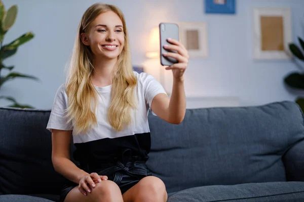 Bella donna che utilizza il suo smartphone in soggiorno — Foto Stock