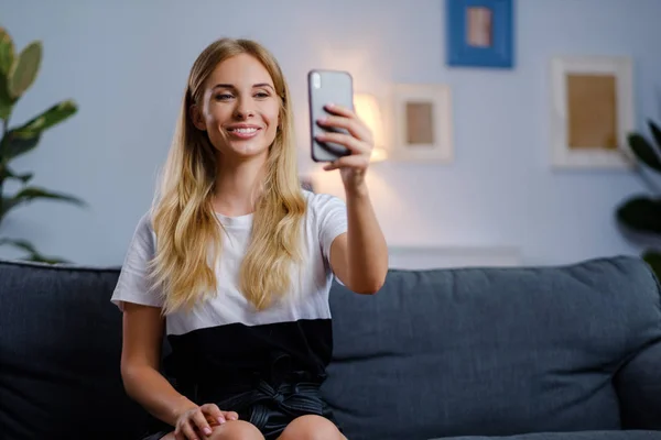 Hermosa mujer usando su teléfono inteligente en la sala de estar — Foto de Stock