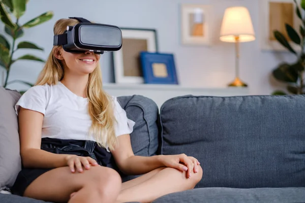 Atractiva mujer joven con auriculares VR haciendo gestos y sonriendo —  Fotos de Stock