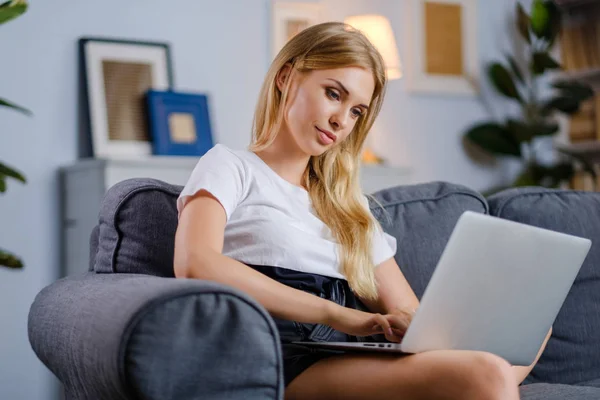 Vacker kvinna som använder laptop sitter på mysig soffa — Stockfoto