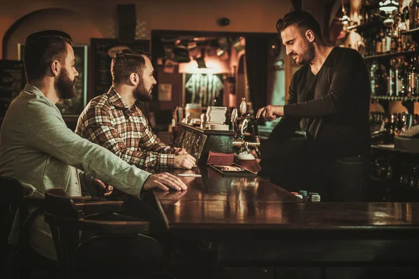 Alte Freunde amüsieren sich und trinken Bier vom Fass an der Theke in der Kneipe. — Stockfoto