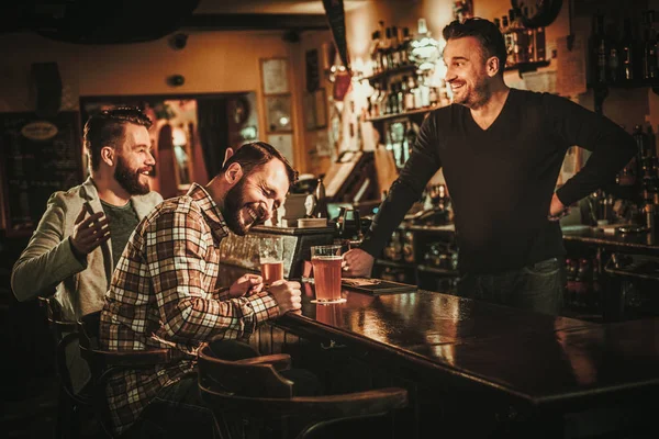 Vecchi amici si divertono e bevono birra alla spina al bancone del bar nel pub . — Foto Stock