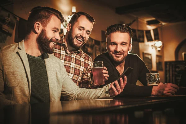 Старі друзі розважаються і п'ють пиво за барною стійкою в пабі . — стокове фото