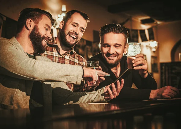 Vecchi amici si divertono e bevono birra alla spina al bancone del bar nel pub . — Foto Stock