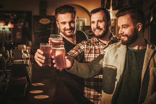 Velhos amigos se divertindo e bebendo cerveja rascunho no balcão de bar no pub . — Fotografia de Stock