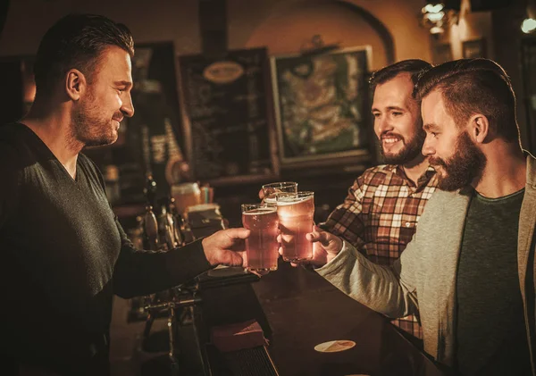 Старые друзья веселятся и пьют пиво за стойкой бара в пабе . — стоковое фото