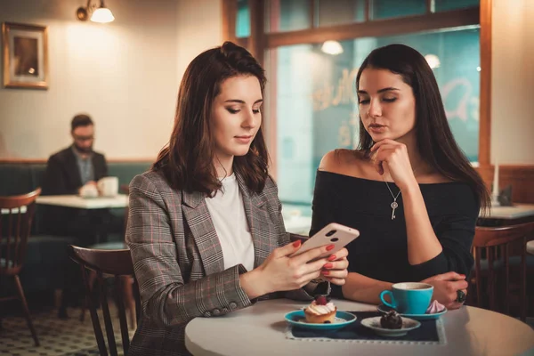Zwei schöne Mädchen tratschen im Café — Stockfoto