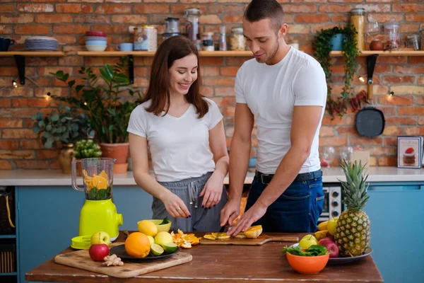 Jovem casal fazendo smoothie na cozinha — Fotografia de Stock