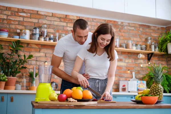 Молодая пара делает смузи на кухне — стоковое фото