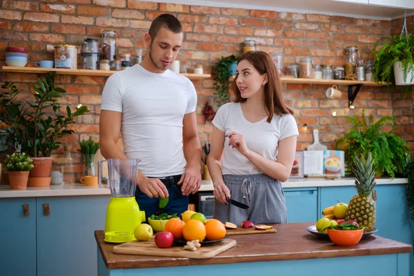 Jovem casal fazendo smoothie na cozinha — Fotografia de Stock