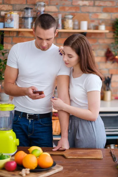 Молодая пара делает смузи на кухне — стоковое фото