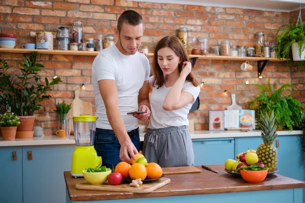 Young couple making smoothie in kitchen — Stock Photo, Image