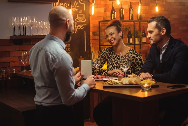 Paar praten met barman achter toog in een café — Stockfoto