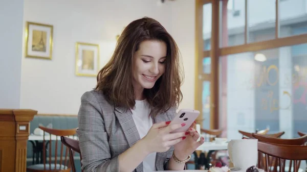 Beaufitul chica sonriente con teléfono celular en un café —  Fotos de Stock