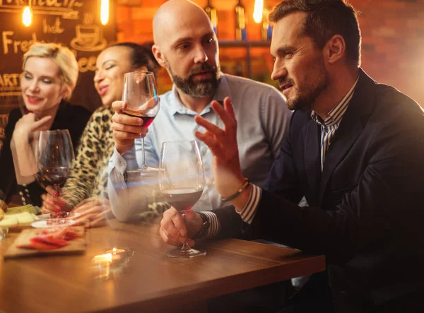 Группа друзей весело разговаривает за барной стойкой в кафе — стоковое фото