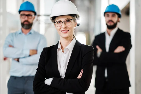 Engineers in hardhats posing in new building — Stock Photo, Image