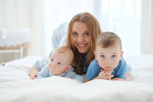 Felice madre di mezza età con i suoi figli in un letto — Foto Stock