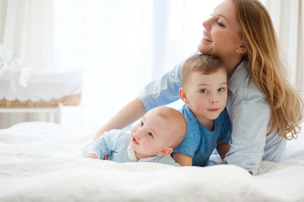 Felice madre di mezza età con i suoi figli in un letto — Foto Stock