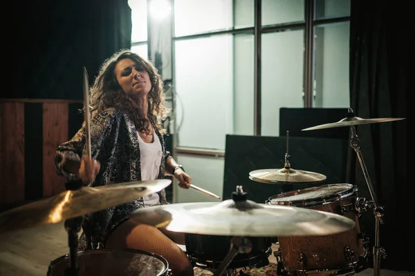 Woman setting drums during music band rehearsal