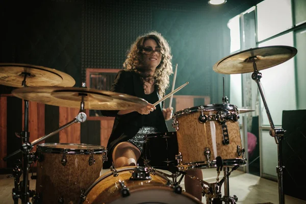 Woman playing drums during music band rehearsal