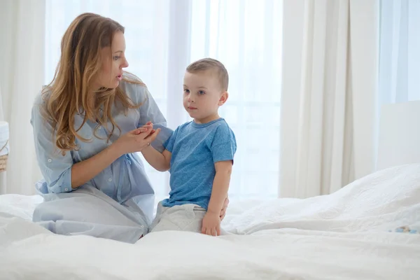 Feliz madre de mediana edad con su hijo en una cama —  Fotos de Stock