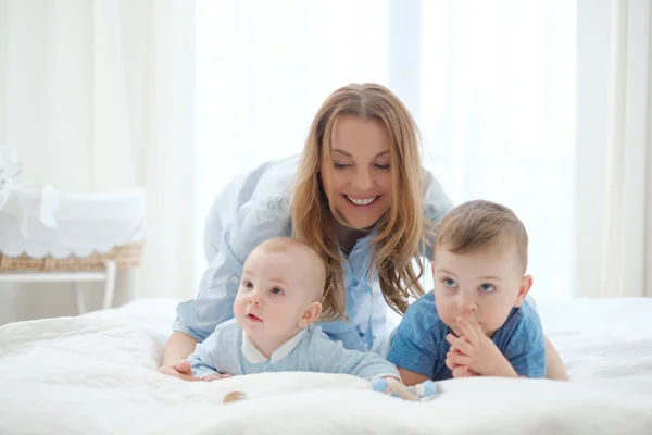 Felice madre di mezza età con i suoi figli in un letto — Foto Stock