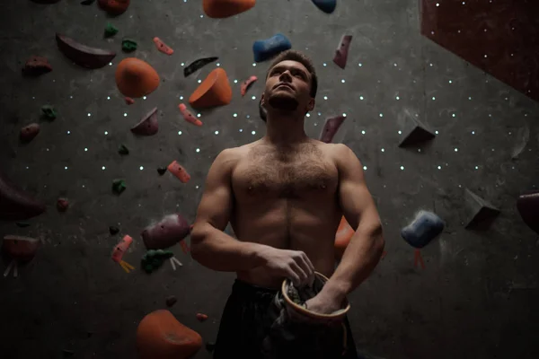 Uomo atletico che usa il gesso prima di arrampicarsi in una palestra di boulder — Foto Stock