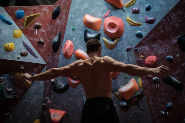 Hombre atlético estirándose antes de escalar en un gimnasio de bouldering — Foto de Stock