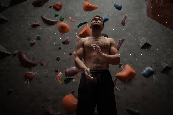 Hombre atlético usando tiza antes de escalar en un gimnasio de bouldering —  Fotos de Stock