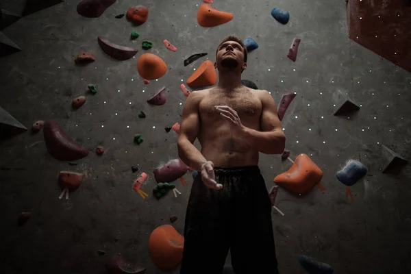 Uomo atletico che usa il gesso prima di arrampicarsi in una palestra di boulder — Foto Stock