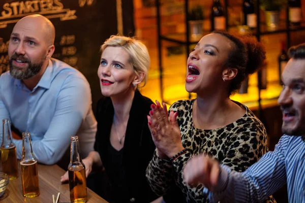 Група друзів дивиться телевізор у кафе за барною стійкою — стокове фото
