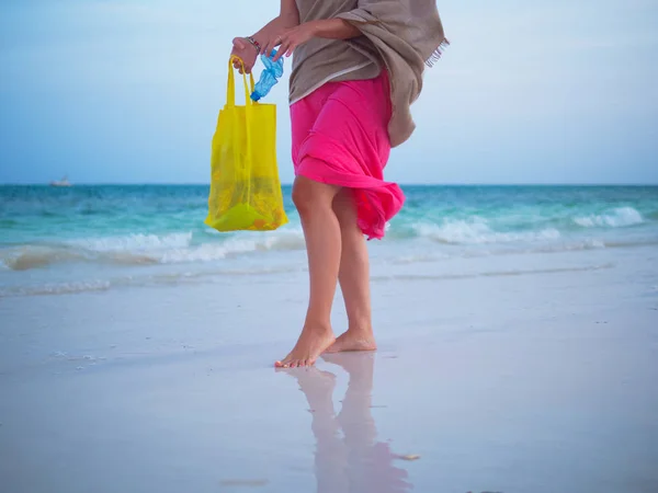 Donna che raccoglie rifiuti di plastica sulla spiaggia . — Foto Stock