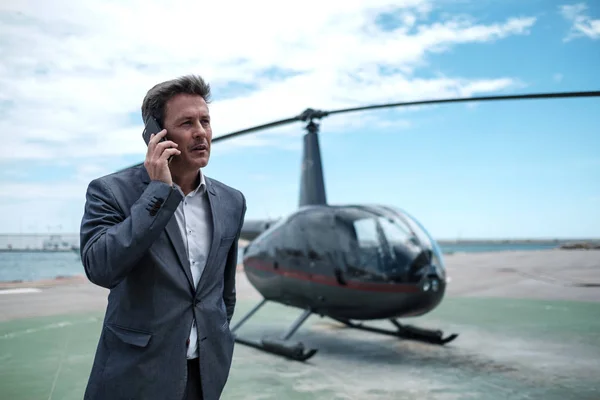 Homme d'affaires parlant sur un téléphone portable près d'un hélicoptère privé — Photo