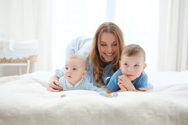 Feliz madre de mediana edad con sus hijos en una cama — Foto de Stock