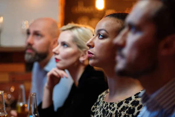 Group of friends watching tv in a cafe behind bar counter — Stock Photo, Image