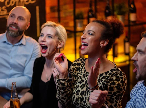 Grupo de amigos viendo la televisión en un café detrás del mostrador de bar —  Fotos de Stock