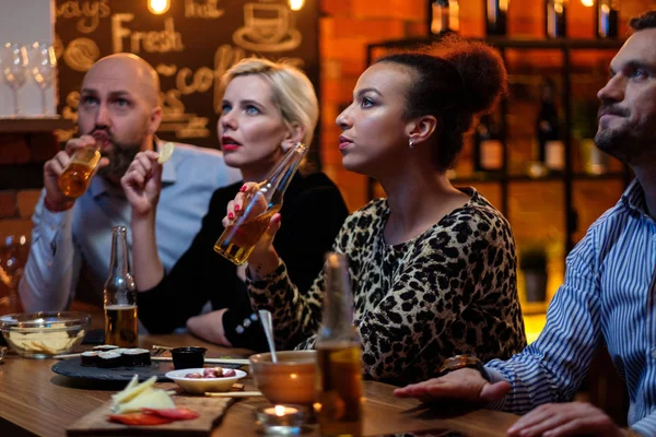 Grupo de amigos assistindo tv em um café atrás do balcão do bar — Fotografia de Stock