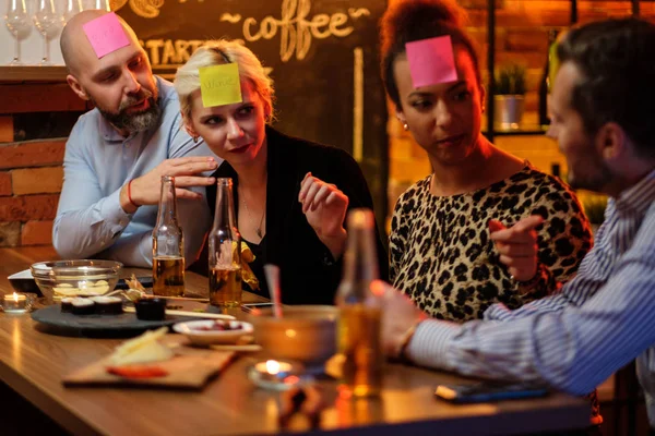 Group of friends playing sticky head game behind bar counter in a cafe — Stock Photo, Image