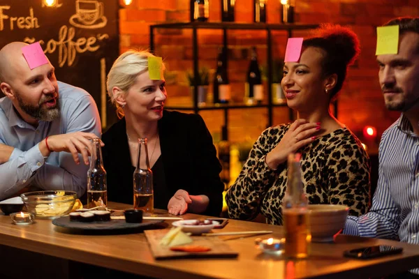 Grupo de amigos jogando jogo de cabeça pegajosa atrás do balcão de bar em um café — Fotografia de Stock