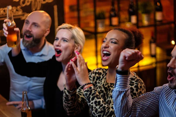 Grupo de amigos viendo la televisión en un café detrás del mostrador de bar —  Fotos de Stock