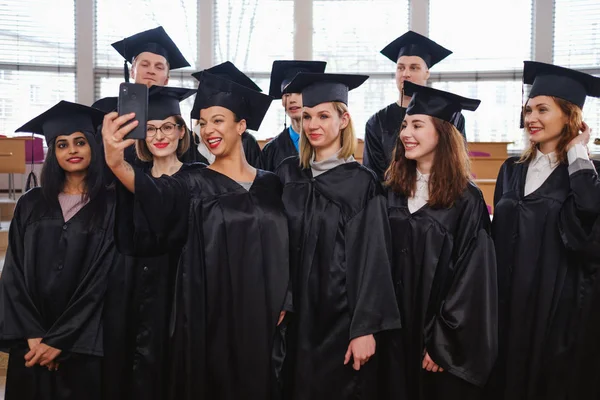 Groupe multi-ethnique d'étudiants diplômés prenant selfie — Photo