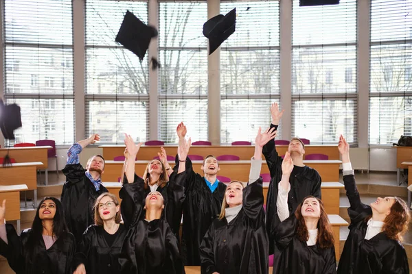 Groupe multi ethnique d'étudiants diplômés jetant des chapeaux — Photo