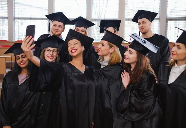 Grupo étnico multi de estudantes graduados que tomam selfie — Fotografia de Stock