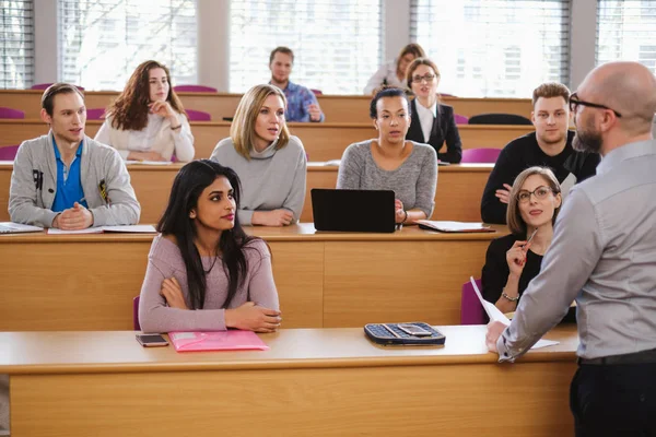 Chargé de cours et groupe multinational d'étudiants dans un auditorium — Photo