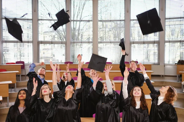 Groupe multi ethnique d'étudiants diplômés jetant des chapeaux — Photo