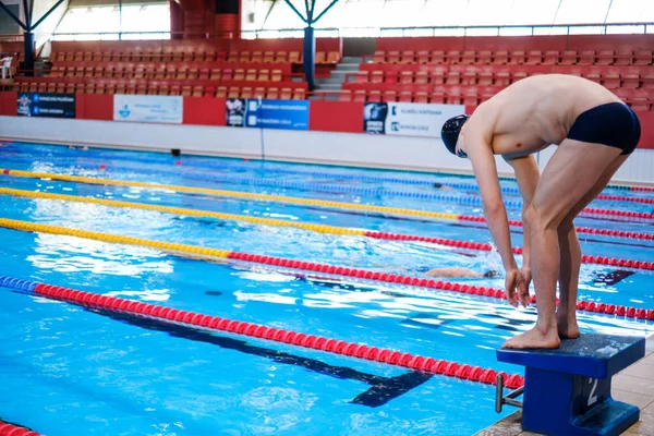 肌肉发达的游泳运动员准备从游泳池的起跑线上跳下 — 图库照片