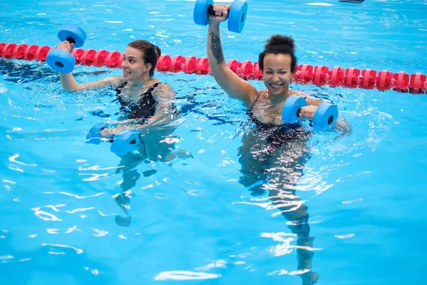 Pareja multiracial asistiendo a clases de aeróbic acuático en una piscina —  Fotos de Stock