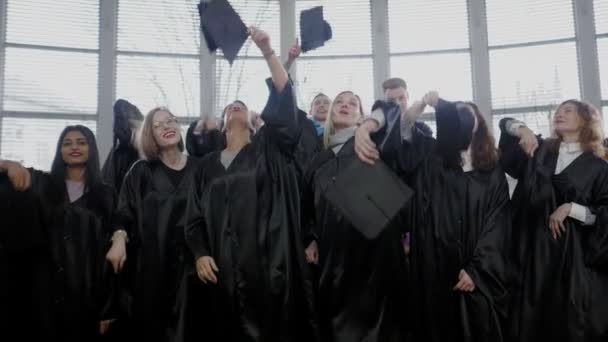 Multi grupo étnico de estudiantes graduados lanzando sombreros — Vídeos de Stock