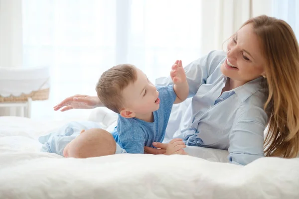 Mãe de meia-idade feliz com seus filhos em uma cama — Fotografia de Stock